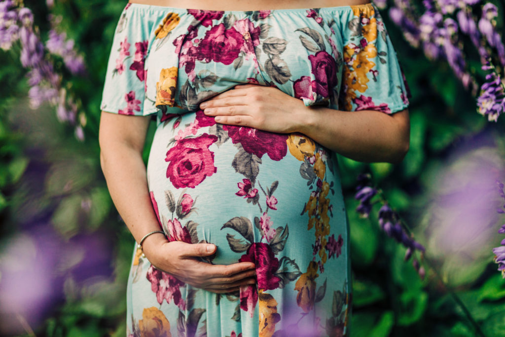 Pregnant woman holding belly during maternity photo session