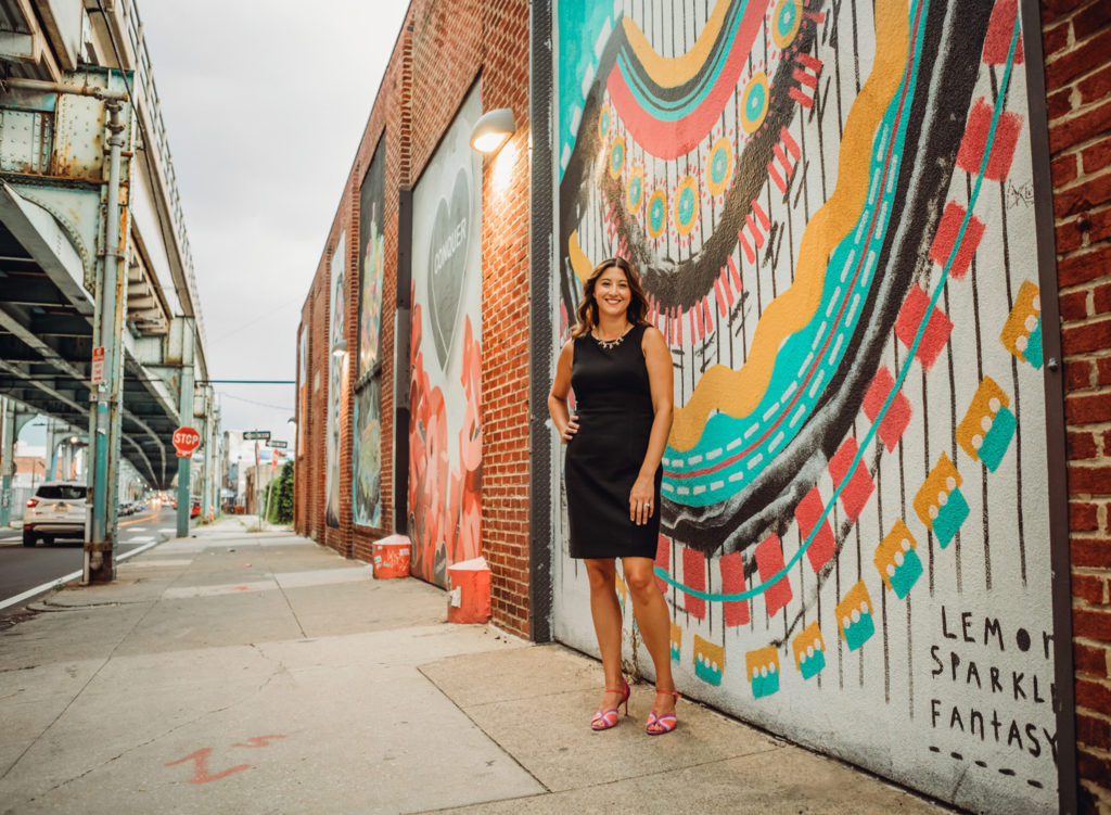 Woman dressed professionally in front of Fishtown Philadelphia mural