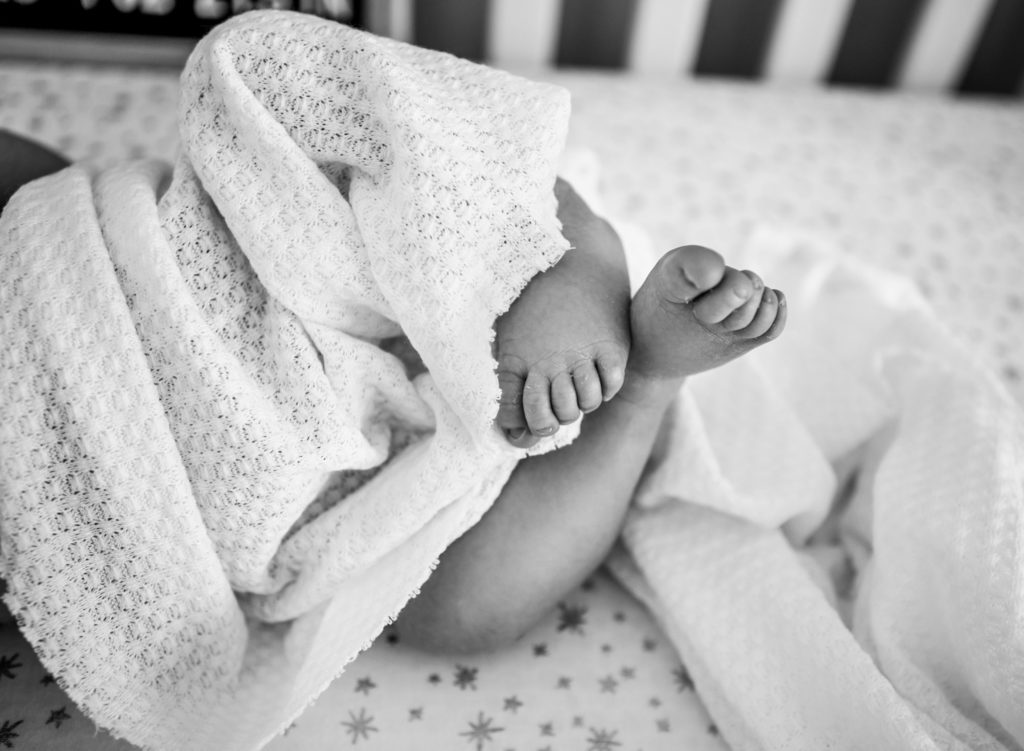 A black and white closeup of a newborn baby's feet.