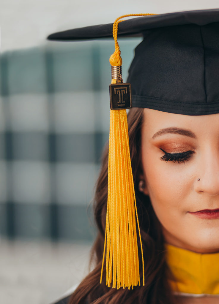 Close up of half of a woman's face in a graduation cap. She is looking down.