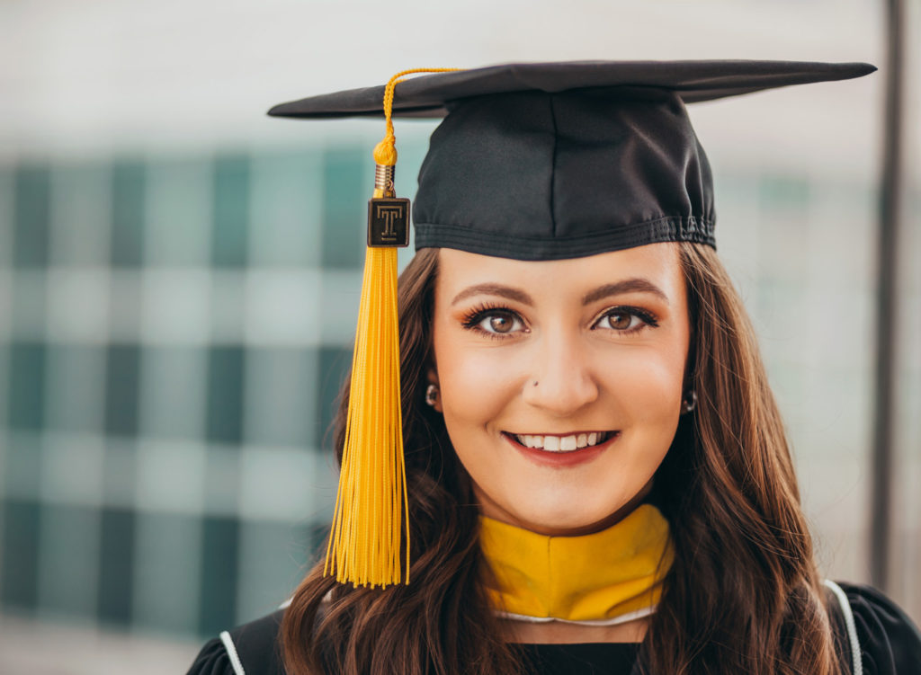 Woman's smiling face with a graduation hat.
