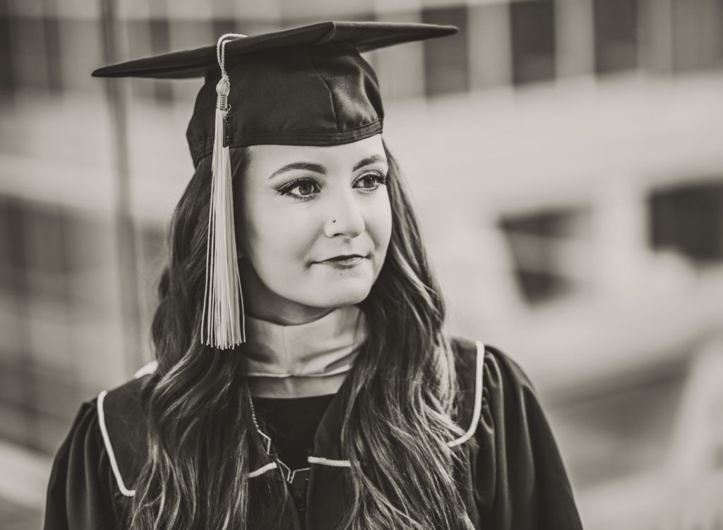 Black and white image of a woman looking off to the side with a graduation hat on her head.
