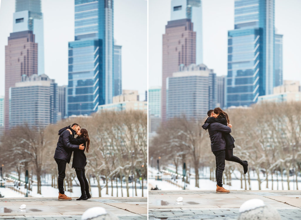 A man and woman hug after a proposal on top of the steps in front of the Philadelphia Museum of Art on a winter day.