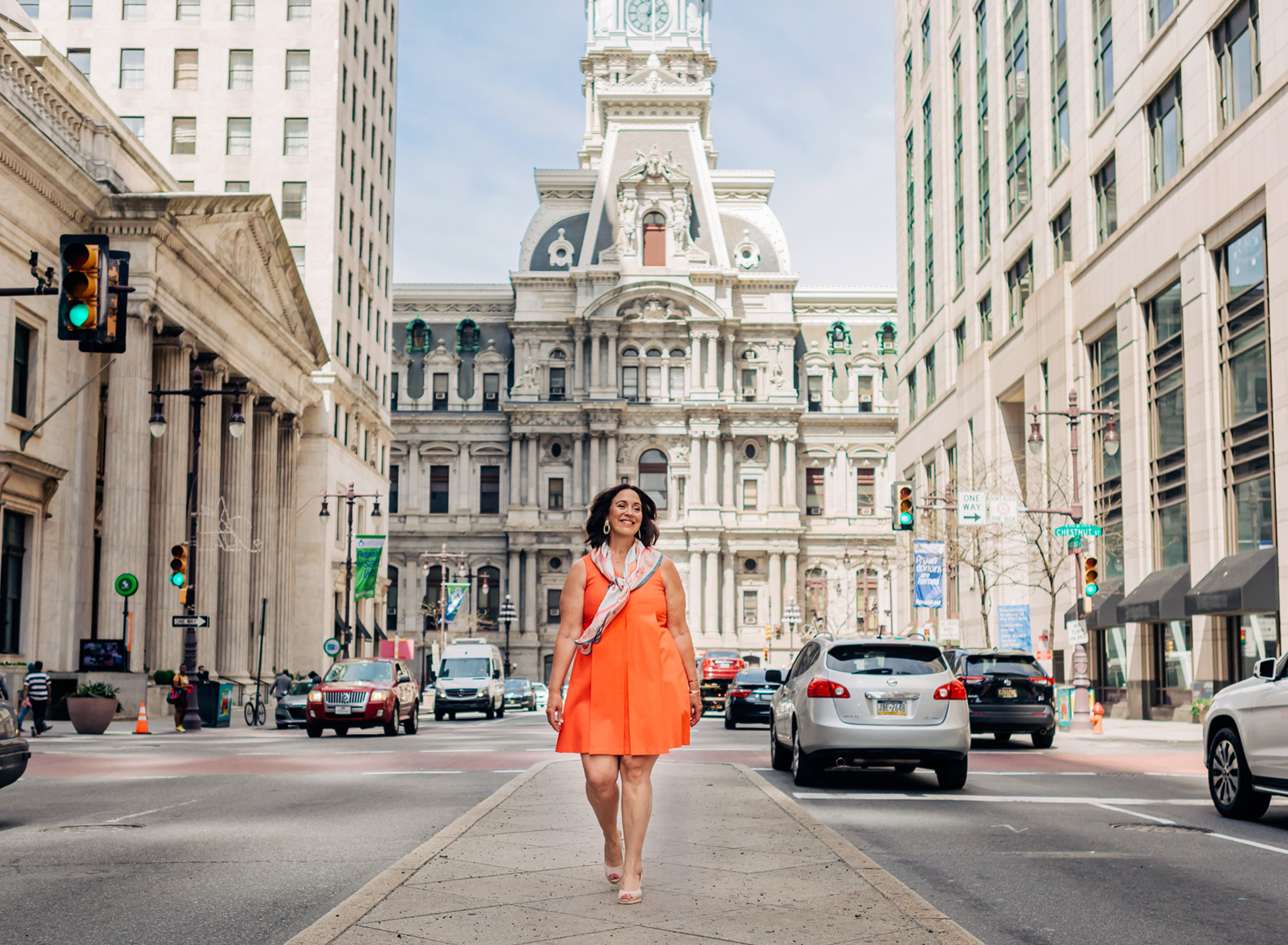 women walking confidently in an orange dress in front of city hall in Philadelphia