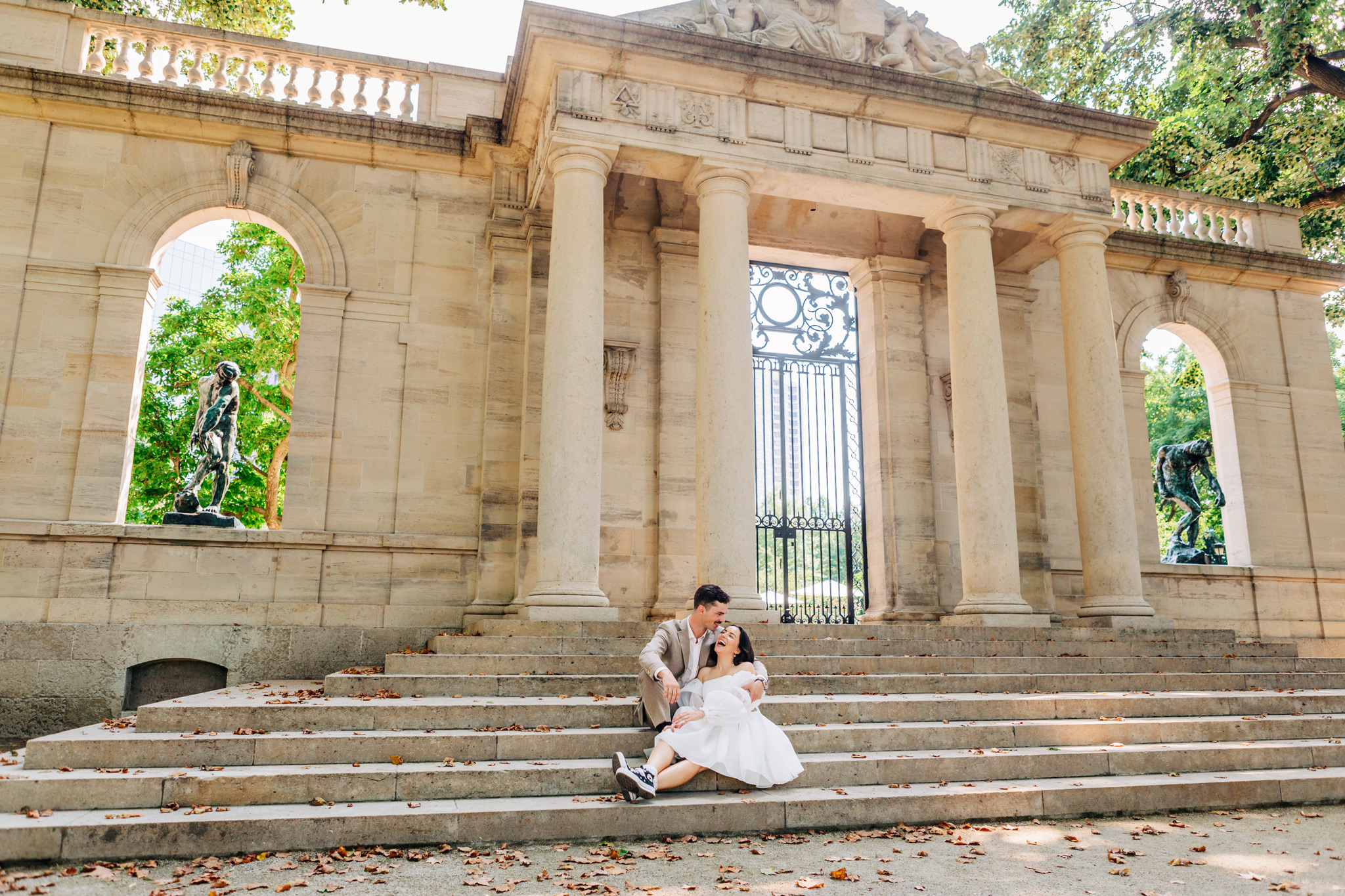 bride and groom sitting and laughing on the steps at the Rodin Museum in Philadelphia