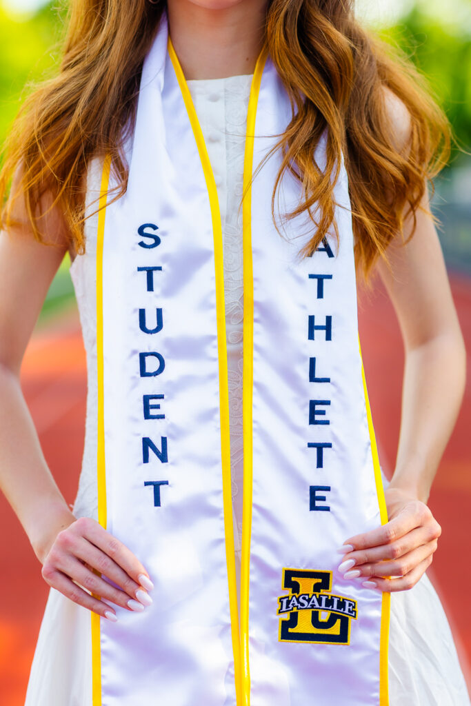 Close-up of a white student athlete graduation stole with embroidered lettering and La Salle University emblem