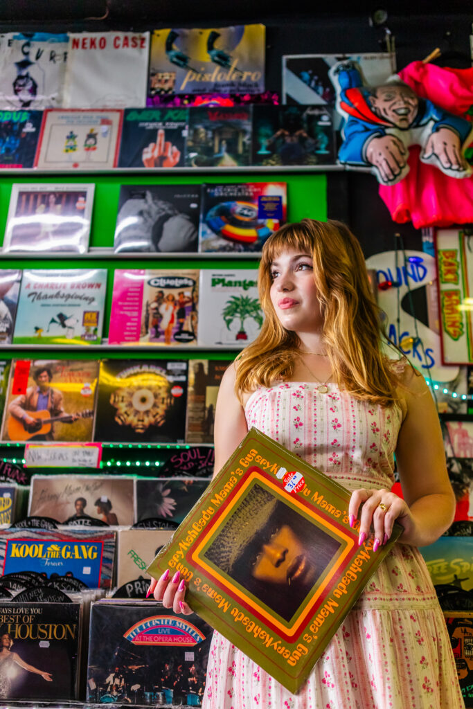 High school senior holding a vinyl record while standing inside Repo Records in Philadelphia.