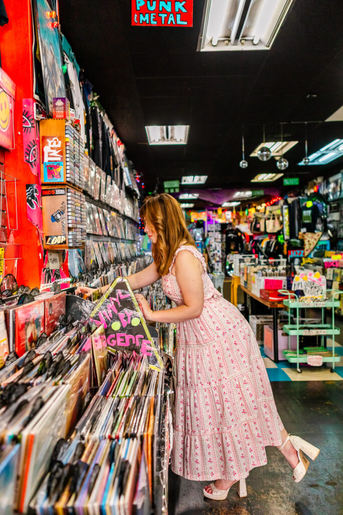 Wide portrait of Lyla browsing vinyl records inside Repo Records on South Street during her Philadelphia senior session.