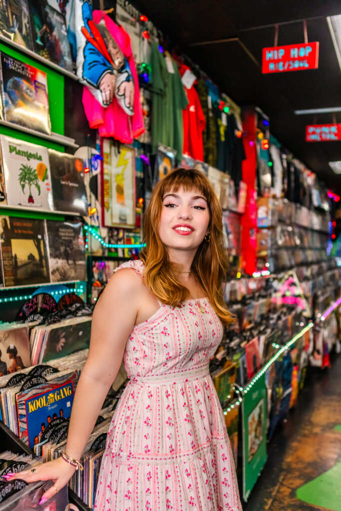 High school senior leaning against record bins inside Repo Records in Philly, surrounded by colorful album covers.